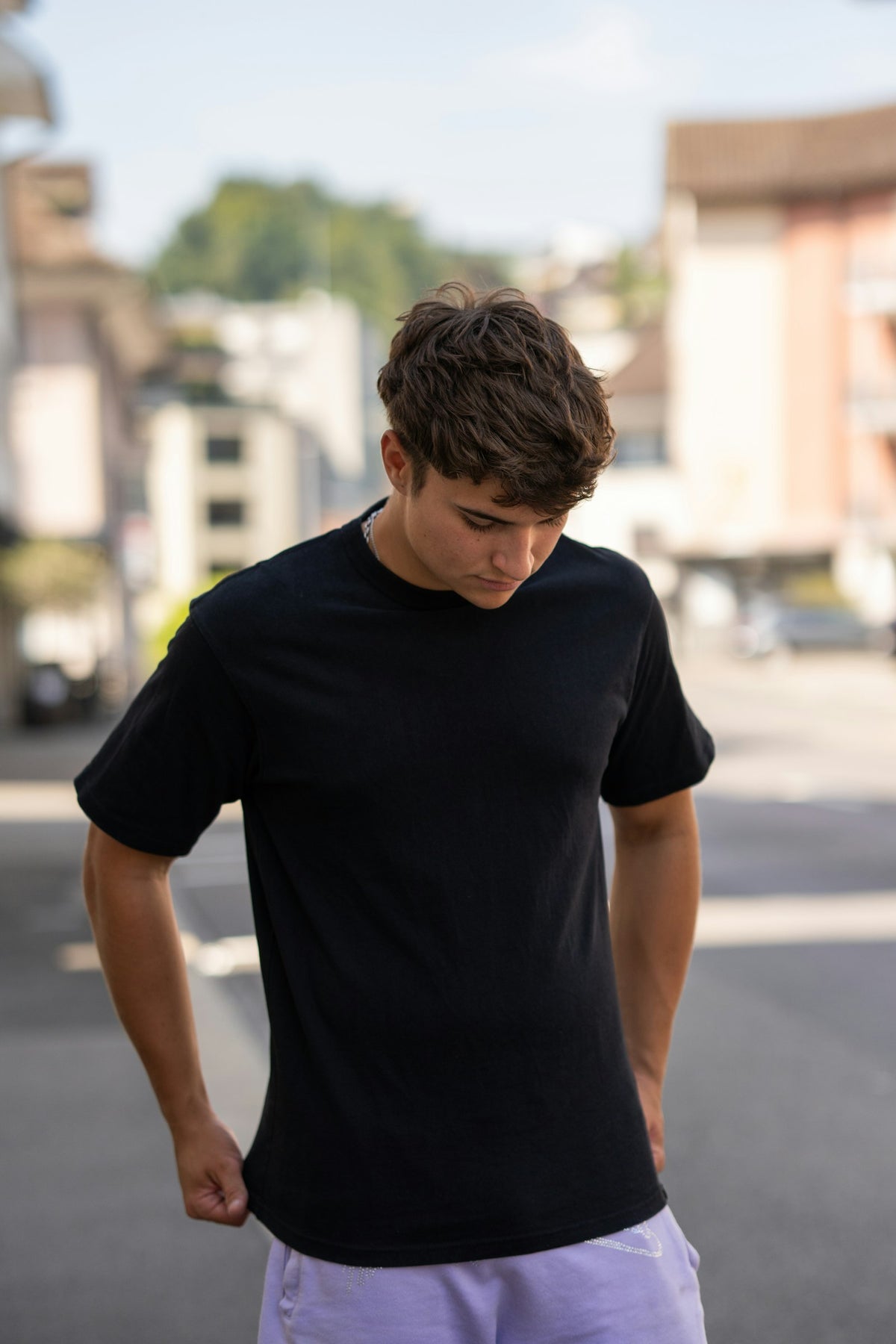 A young man in an oversized black tee on a city street